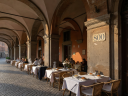 Arched portico in Bologna with outdoor pasta restaurant seating