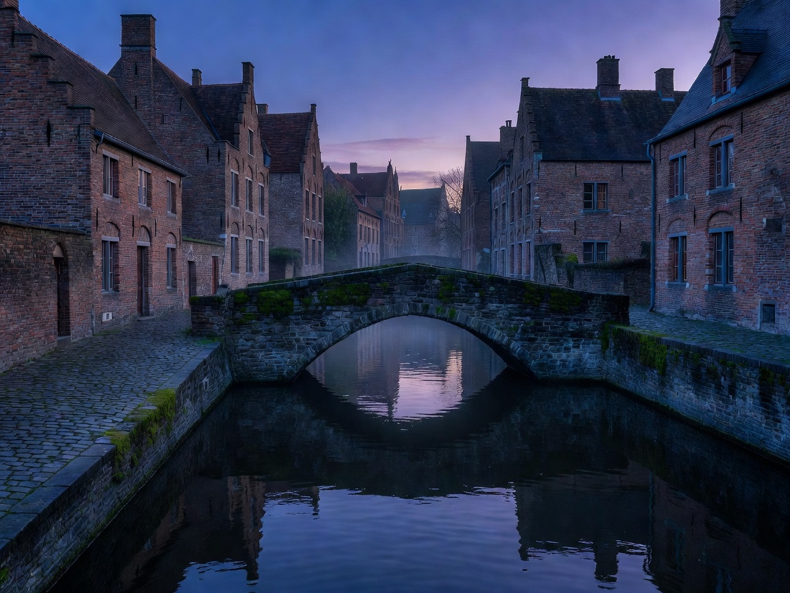 Quiet medieval brick canal and stone bridge in Bruges at dusk